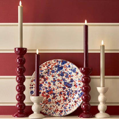 LED battery-powered wax candles, color-matched with lacquered bobbin candlesticks, featuring a real wax exterior, remote control, and flicker mode for a soft twinkle.