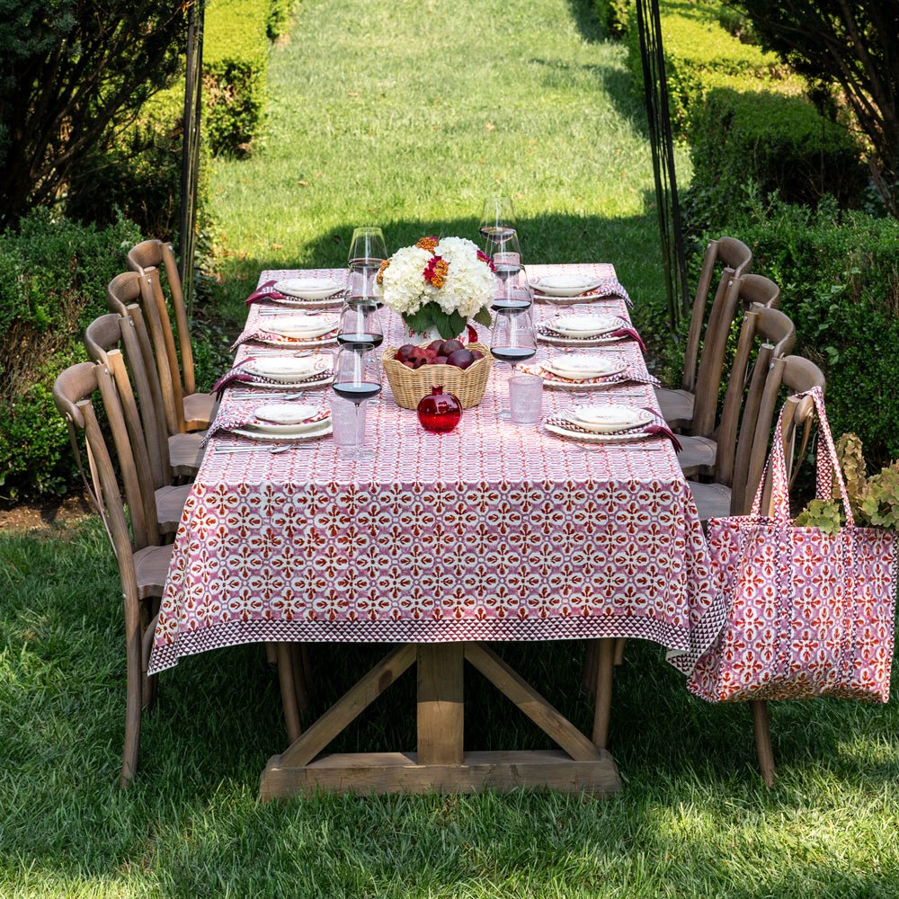 Fleur de Lis Rose Tablecloth with a soft pink pattern and bold purple border, hand-block printed on 100% cotton. Perfect for adding elegance to your dining table. Measures 60" x 120".