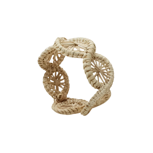 Swirl Napkin Ring, handwoven from Iraca Palm and wire by skilled artisans in Colombia. This piece adds a natural touch to your table. Clean with a damp cloth or toothbrush for best care.