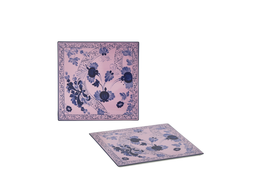 Set of 2 square porcelain placemats in Azalea from the Oriente Italiano collection, featuring a blue carnation motif with hand-painted gold threading against azalea pink porcelain