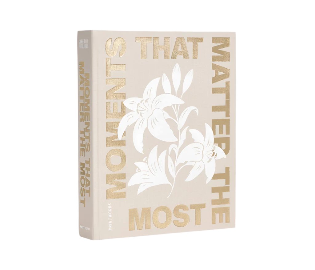 Moments that Matter the Most Coffee Table Photo Album with a beige cloth cover and gold foiled text. Includes 30 white photo paper pages for two 10x15 cm photos per page, made with FSC-certified materials and a black metal binder.