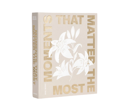 Moments that Matter the Most Coffee Table Photo Album with a beige cloth cover and gold foiled text. Includes 30 white photo paper pages for two 10x15 cm photos per page, made with FSC-certified materials and a black metal binder.