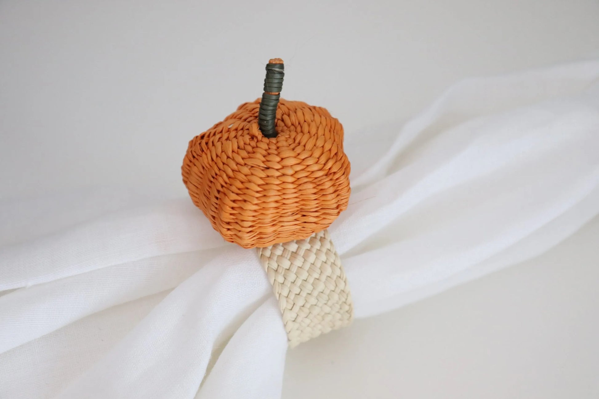 Handcrafted Pumpkin Napkin Ring made from Iraca Palm by artisans in Colombia. This charming autumn decor piece measures 2" x 1.5" and adds a festive touch to any table. Clean with a damp cloth or toothbrush to maintain its beauty.