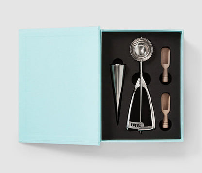 Essential Ice Cream Kit in an elegant book-like box, containing 2 cone shapes, an ice cream scoop, and 2 sprinkle scoops, all made of stainless steel and dishwasher safe. Perfect for hosting ice cream parties.