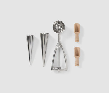 Essential Ice Cream Kit in an elegant book-like box, containing 2 cone shapes, an ice cream scoop, and 2 sprinkle scoops, all made of stainless steel and dishwasher safe. Perfect for hosting ice cream parties.