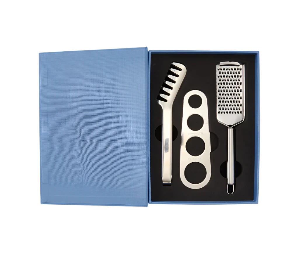 Essential Pasta Kit in an elegant book-like box containing stainless steel spaghetti measurer, serving tongs, and grater—all dishwasher safe for perfect pasta nights.