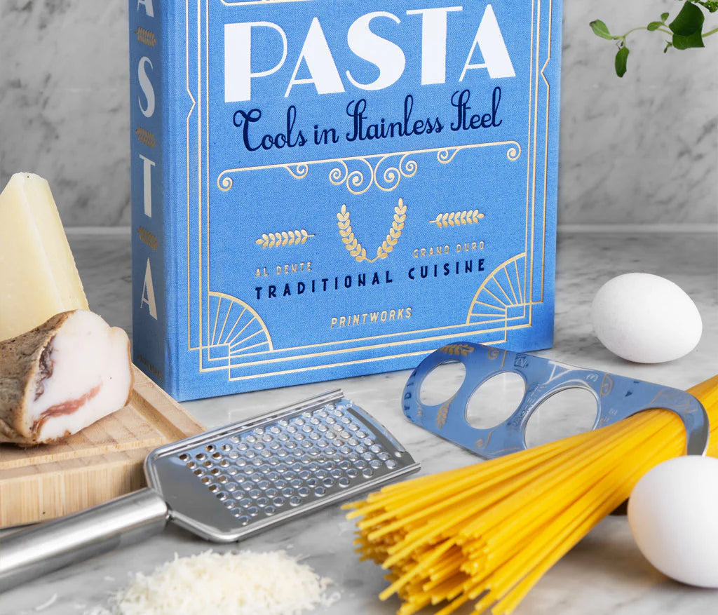 Essential Pasta Kit in an elegant book-like box containing stainless steel spaghetti measurer, serving tongs, and grater—all dishwasher safe for perfect pasta nights.