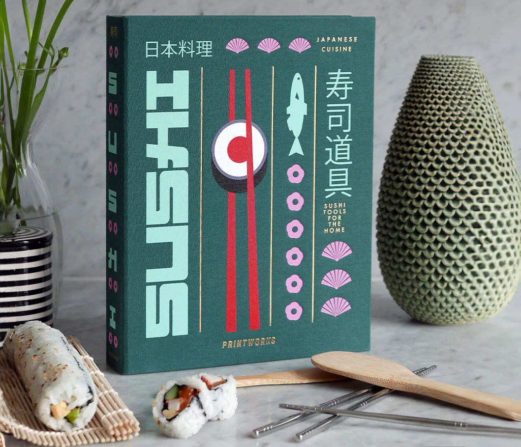 Essential Sushi Kit in a book-like box, featuring a bamboo rice paddle, spreading knife, rolling mat, and 8 chopsticks. Ideal for sushi-making, with all tools dishwasher safe.