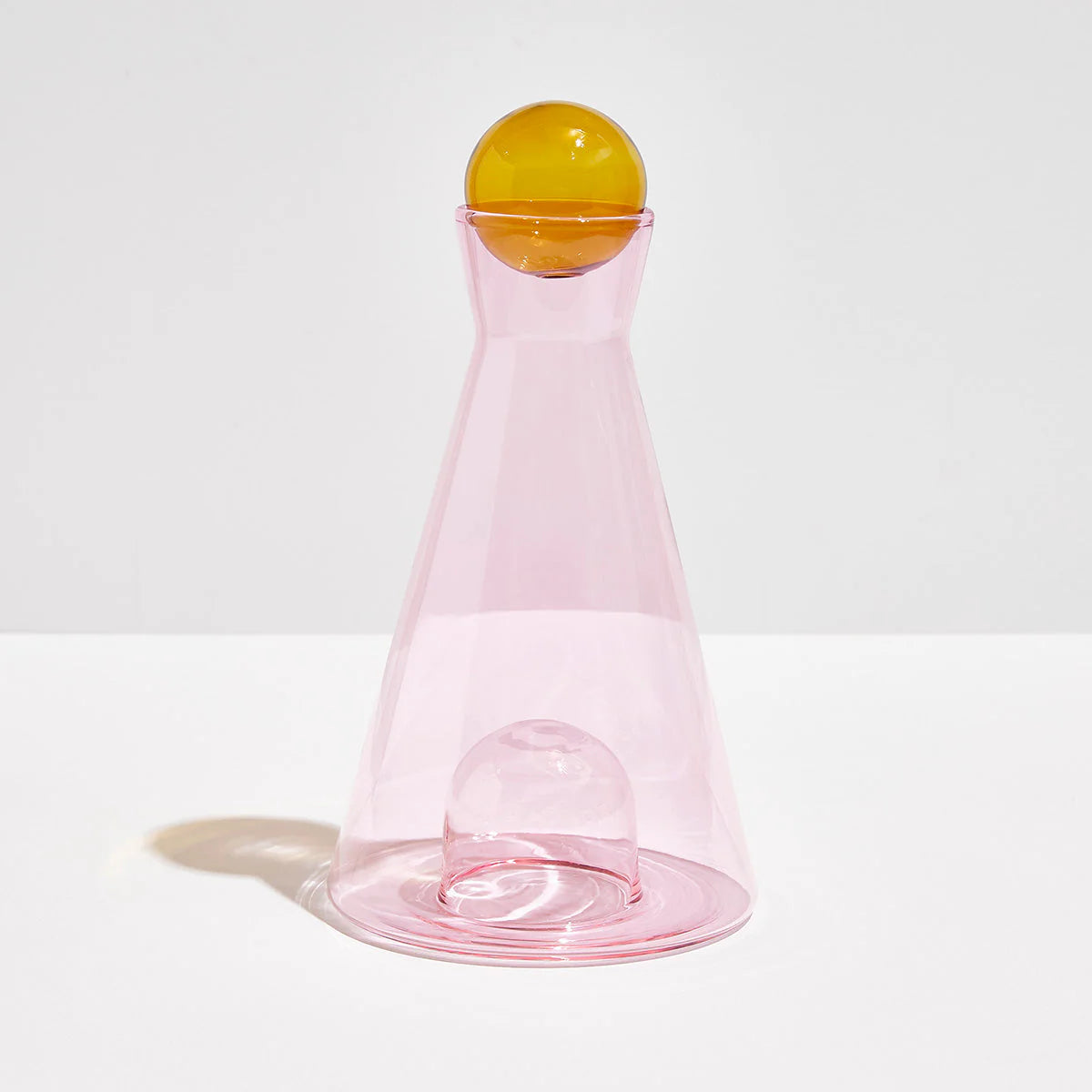 Pink and amber Vice Versa Carafe with a sculptural sphere that can rest in the glass-blown mouth or base, perfect as a centerpiece or stylish serving vessel.