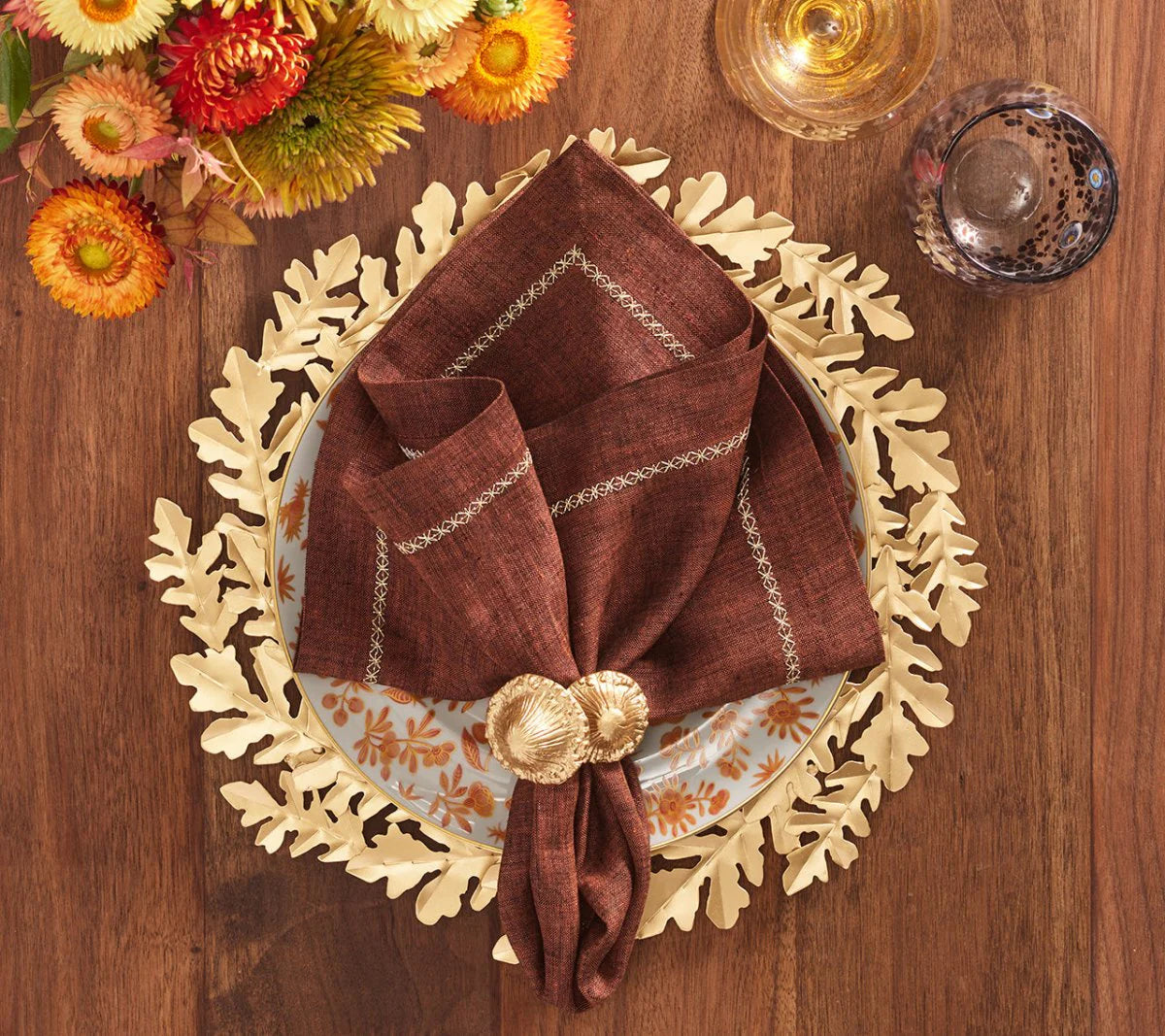 The Sprout Napkin Ring showcases gold-plated metal mushrooms sprouting from a carved wooden base, adding a rustic, organic charm to your fall table setting.